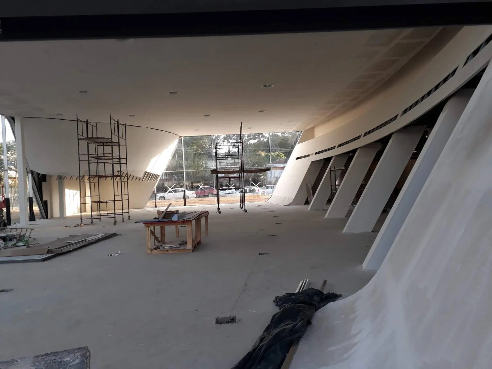 Ambiente em obra, com teto amplo, paredes curvas e andaimes, em registro da ERB.